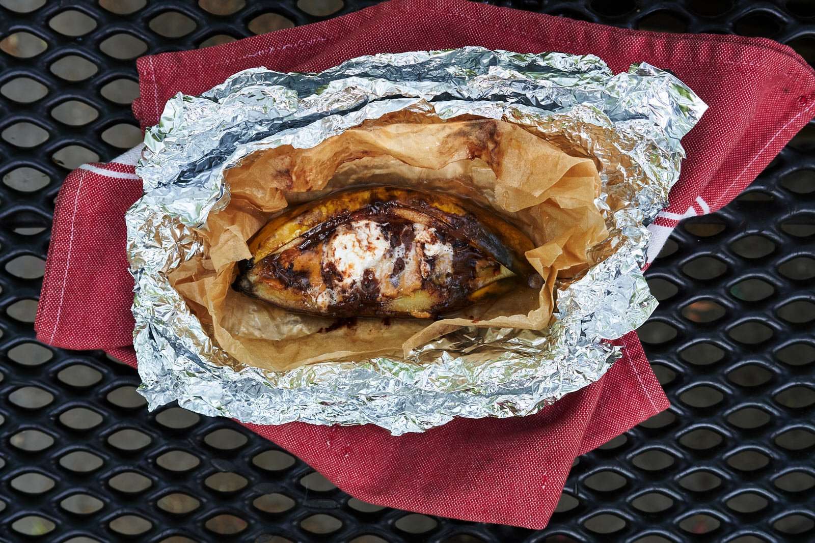 cooked campfire banana boats on a picnic table at camp