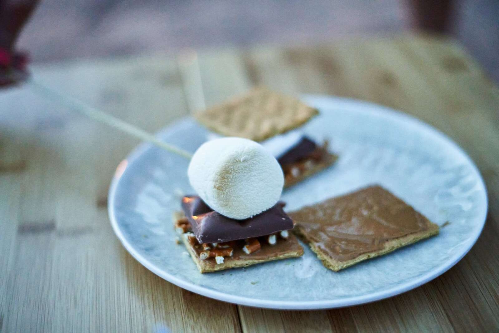 adding a toasted marshmallow on top of chocolate for smores 