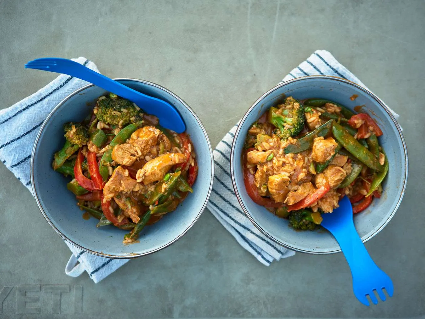two enamel bowls filled with thai chicken curry at camp