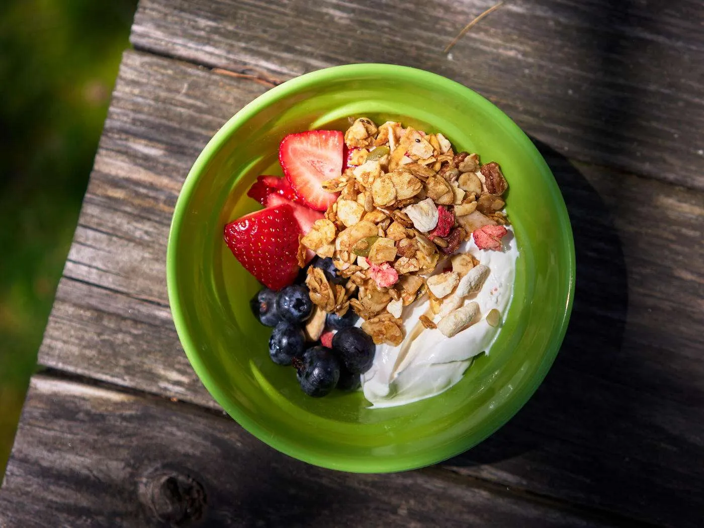 green bowl of yogurt, granola, and fresh berries