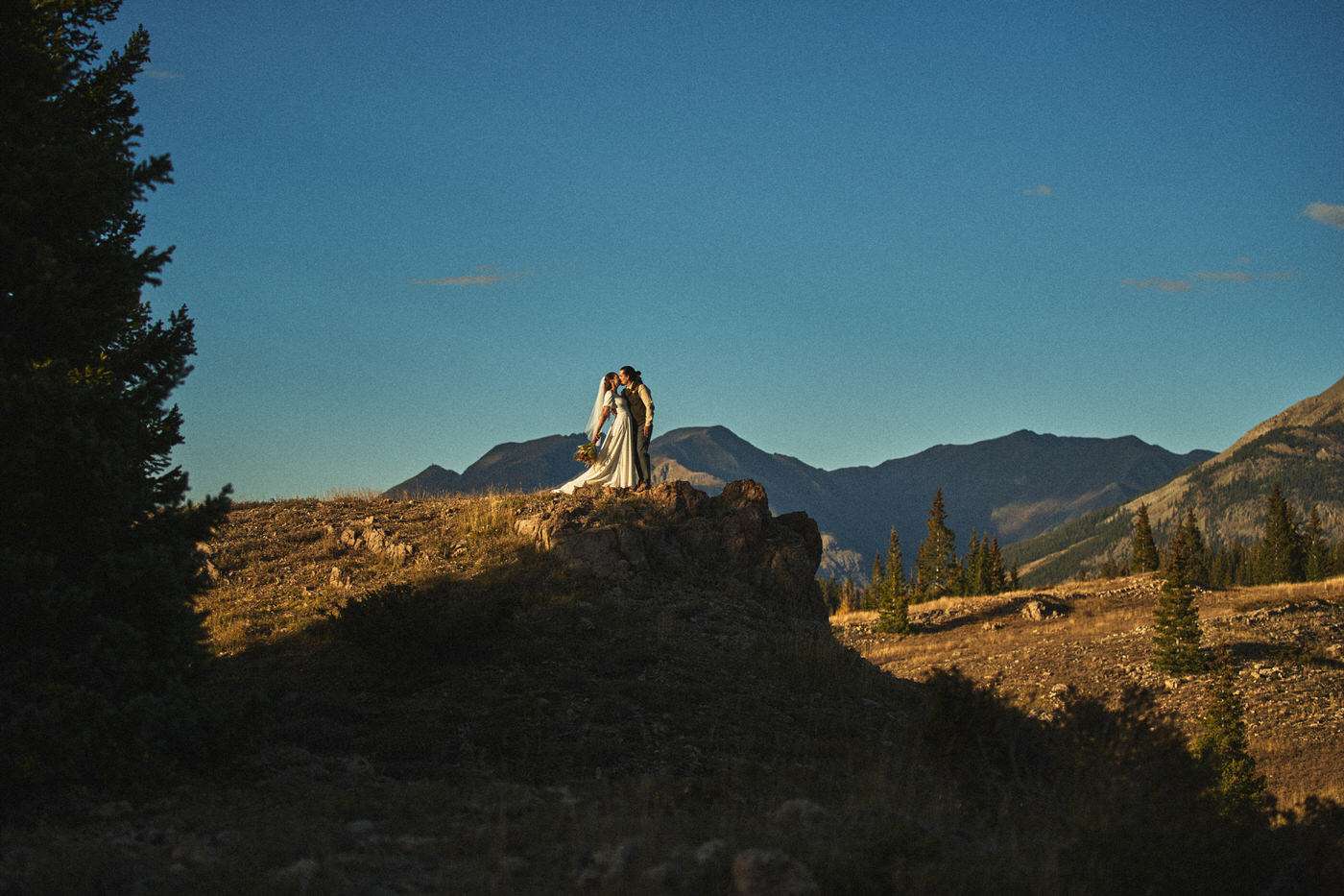 bride and groom kissing in the mountains on their wedding day