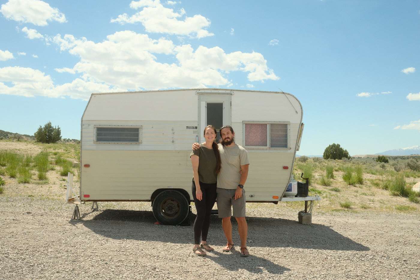 Amanda and Nick standing outside of their vintage camper before the renovation started 