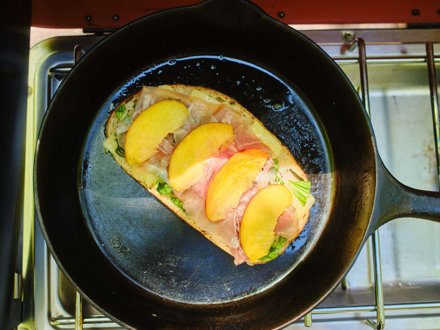cooking peach basil grilled cheese in a cast iron skillet over a camp stove