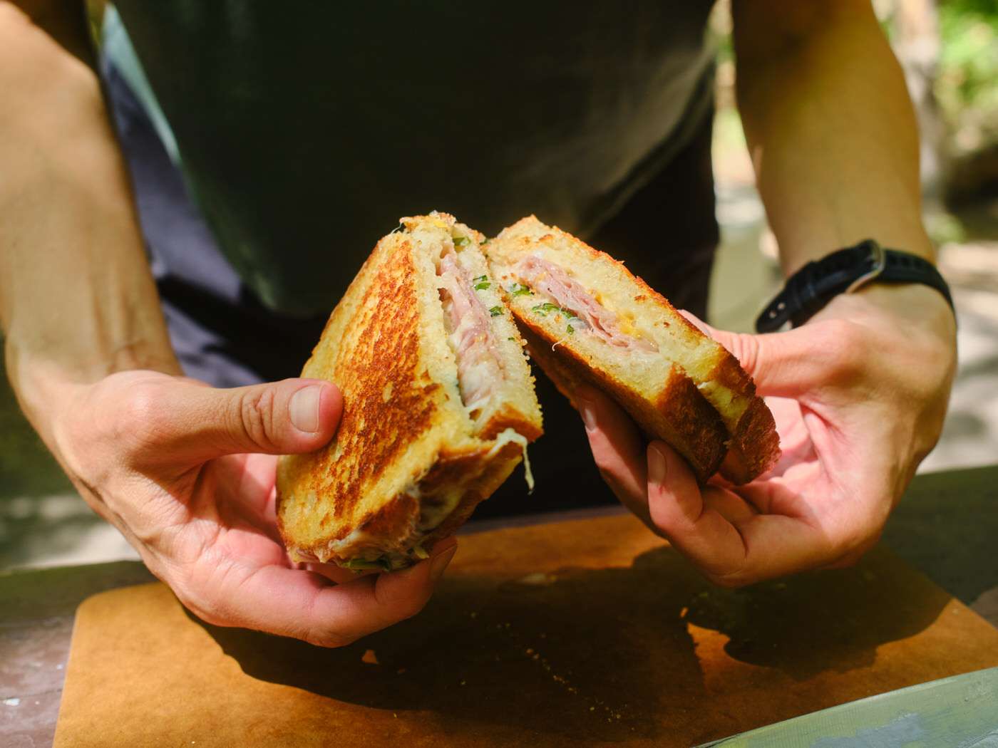 hands holding two halves of peach, basil, and prosciutto grilled cheese