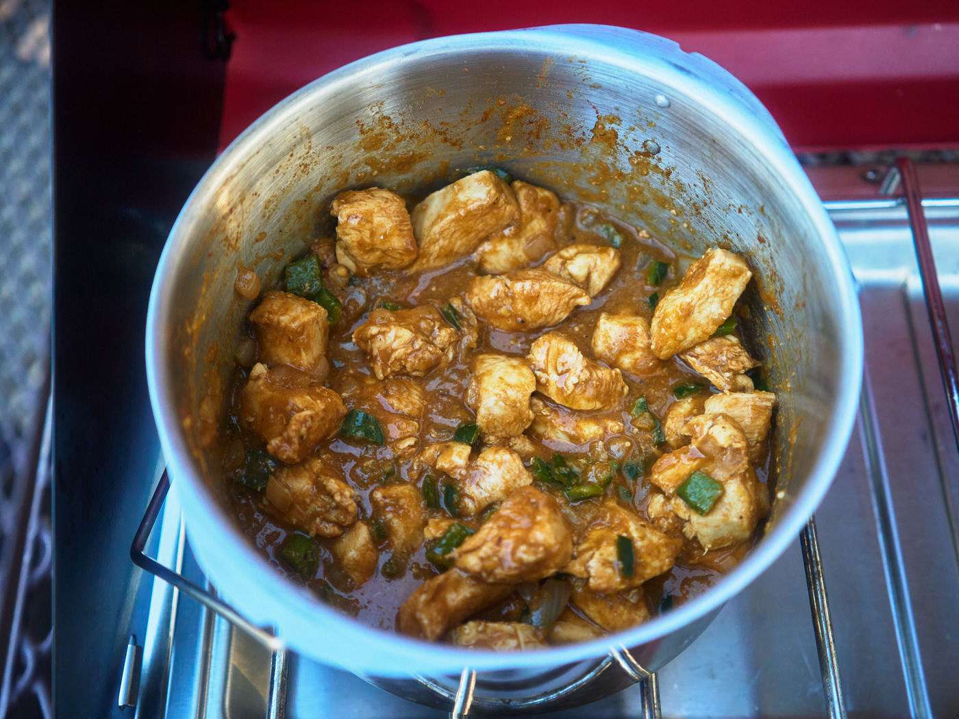 salsa verde chicken cooking in a pot over a propane camp stove