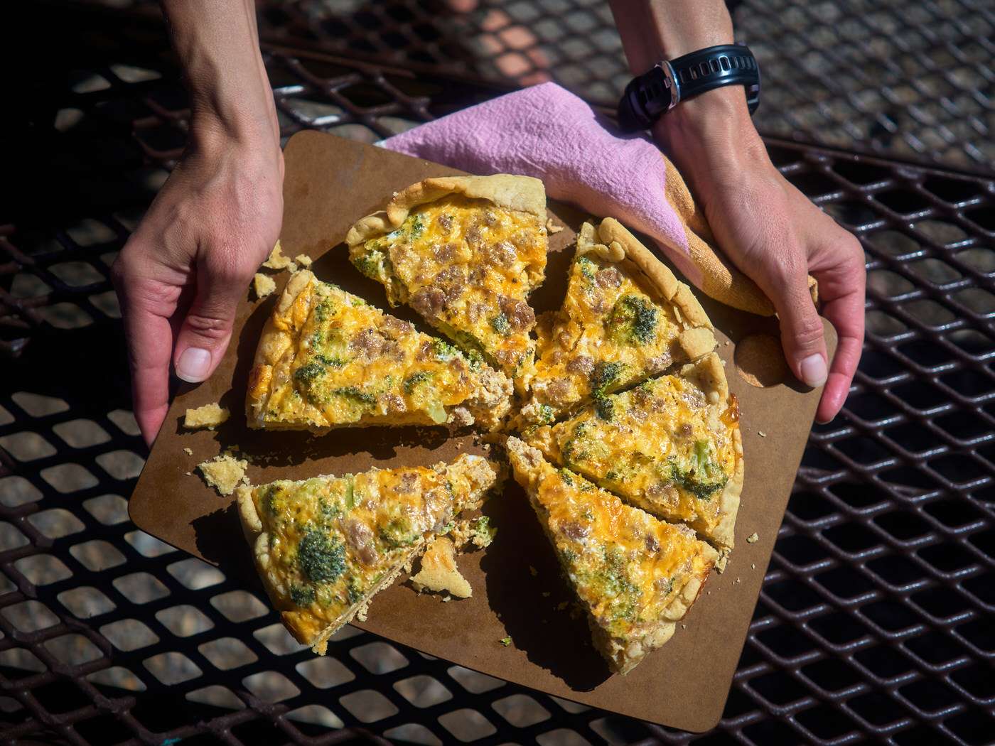 hands holding six slices of dutch oven quiche at camp