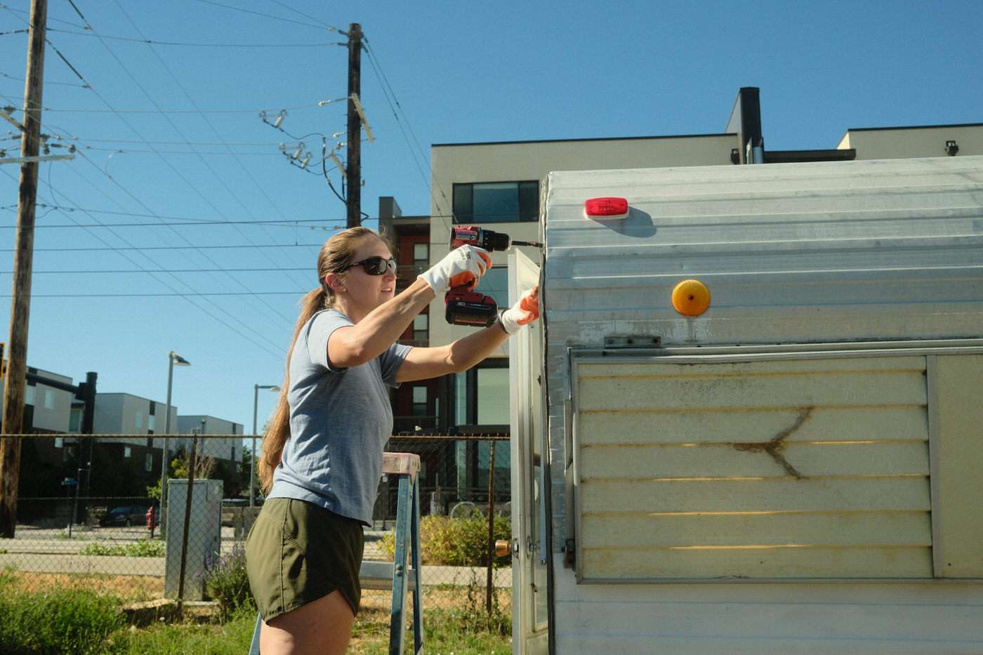 Amanda installing new j-gutter on the exterior of a vintage camping trailer 