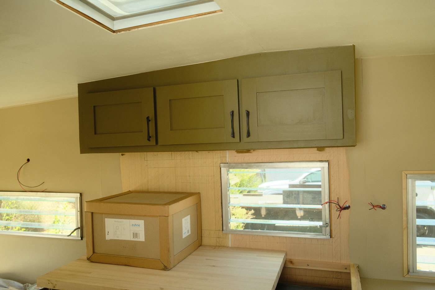 new kitchen cabinets installed and painted green in vintage camper renovation
