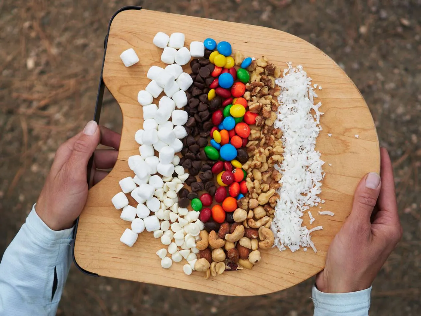 Tray of different campfire cone flavor ideas and filling options including mini marshmallows, chocolate candies, nuts, and coconut