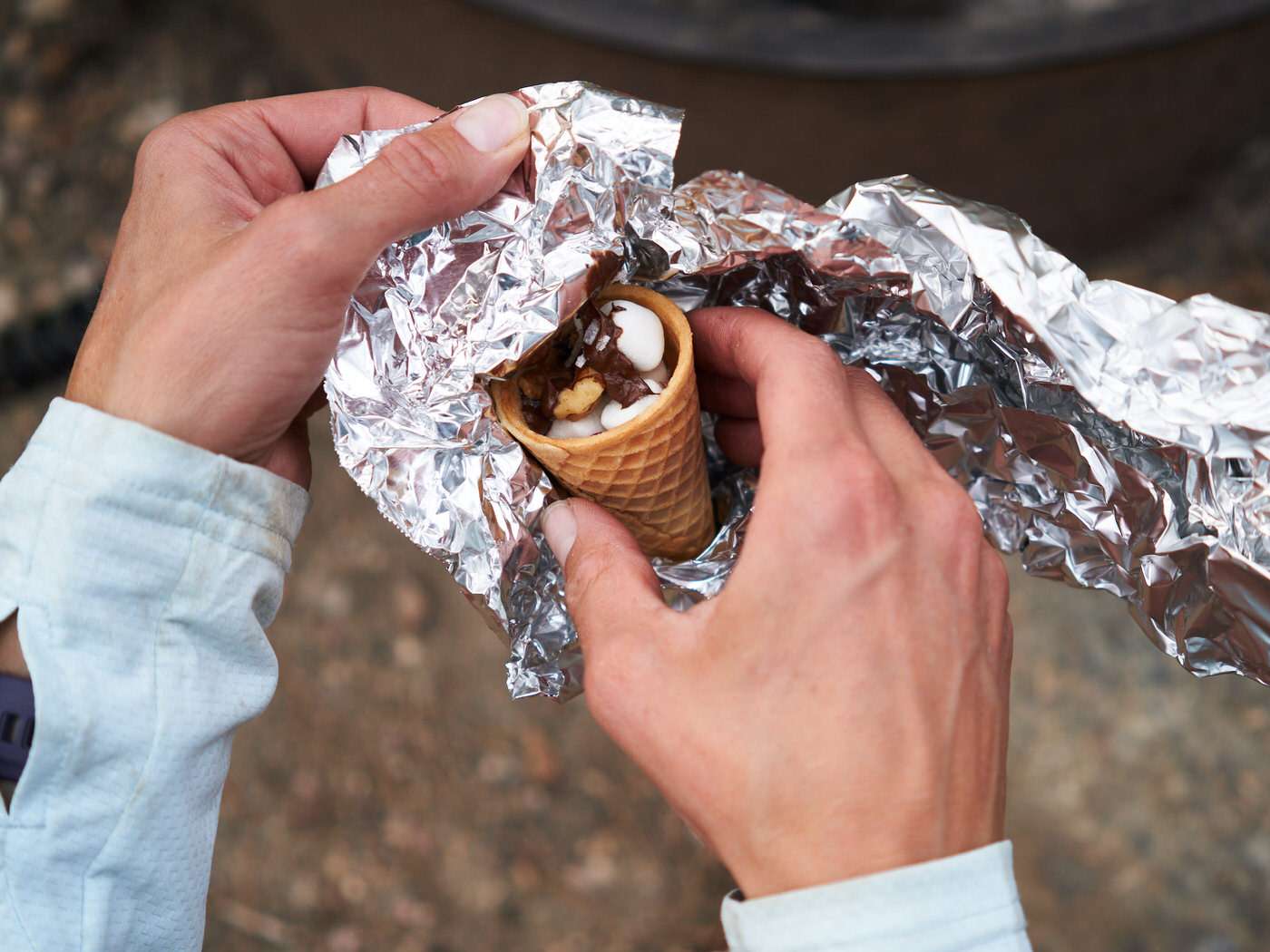 unwrapping a campfire cone from foil after cooking over the campfire 