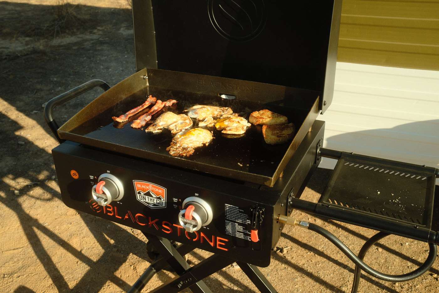 eggs, bacon, and toast cooking on a blackstone griddle while camping 