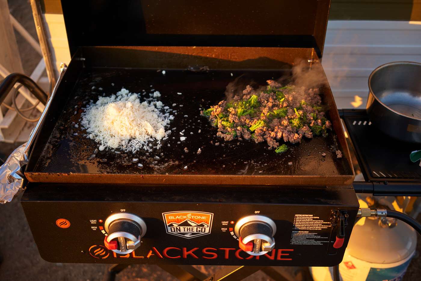 beef, rice, and broccoli cooking over a blackstone grill while camping 