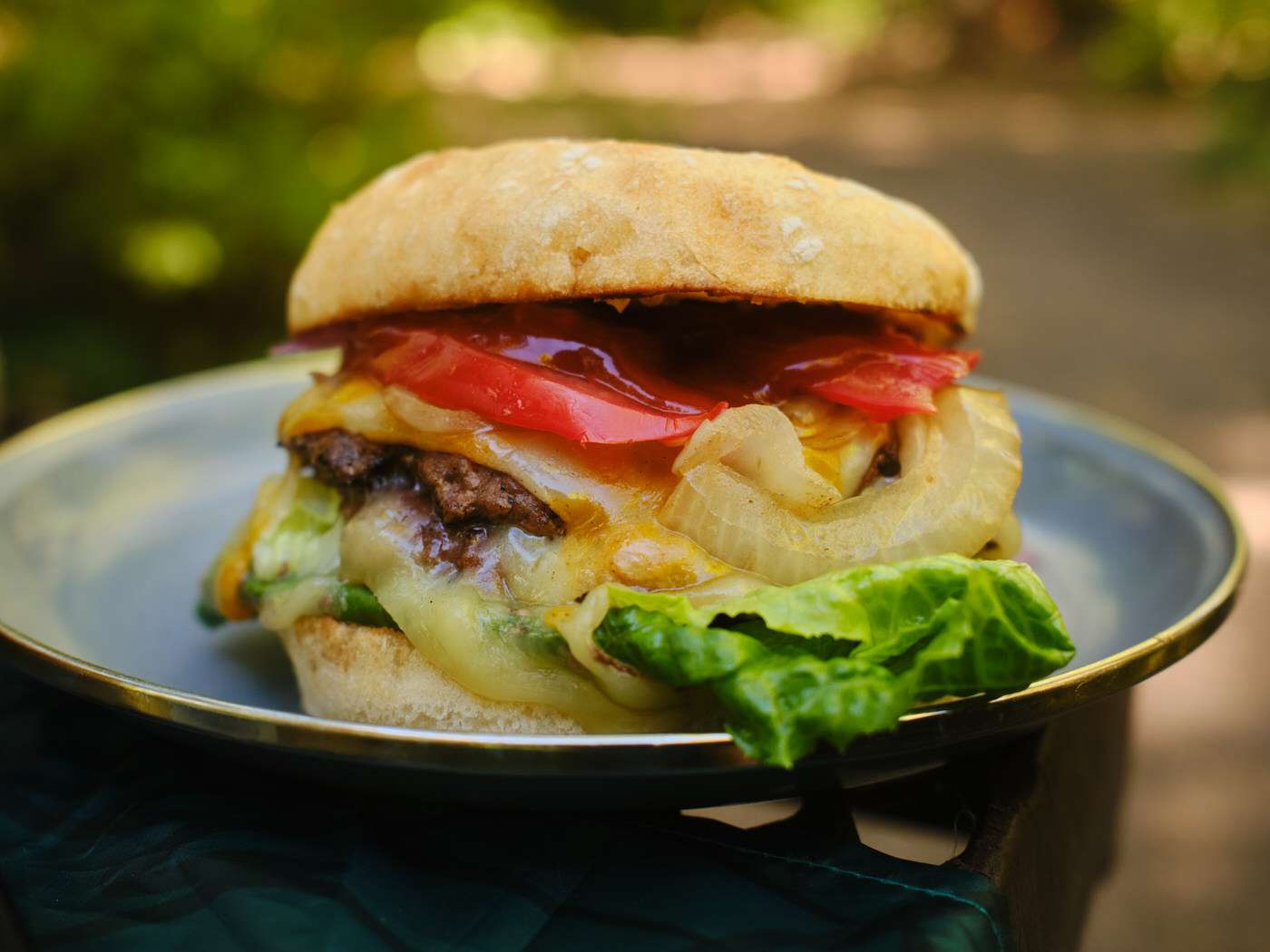 close up of blackstone smashburgers with cheese, lettuce, onions, and tomato 
