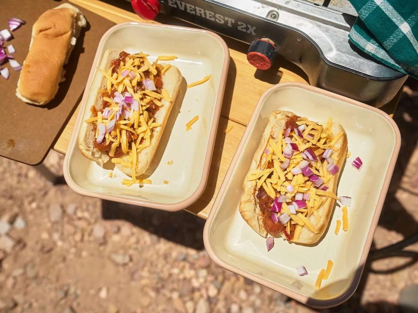 two chili cheese dogs topped with cheddar cheese and red onion for a quick camping dinner