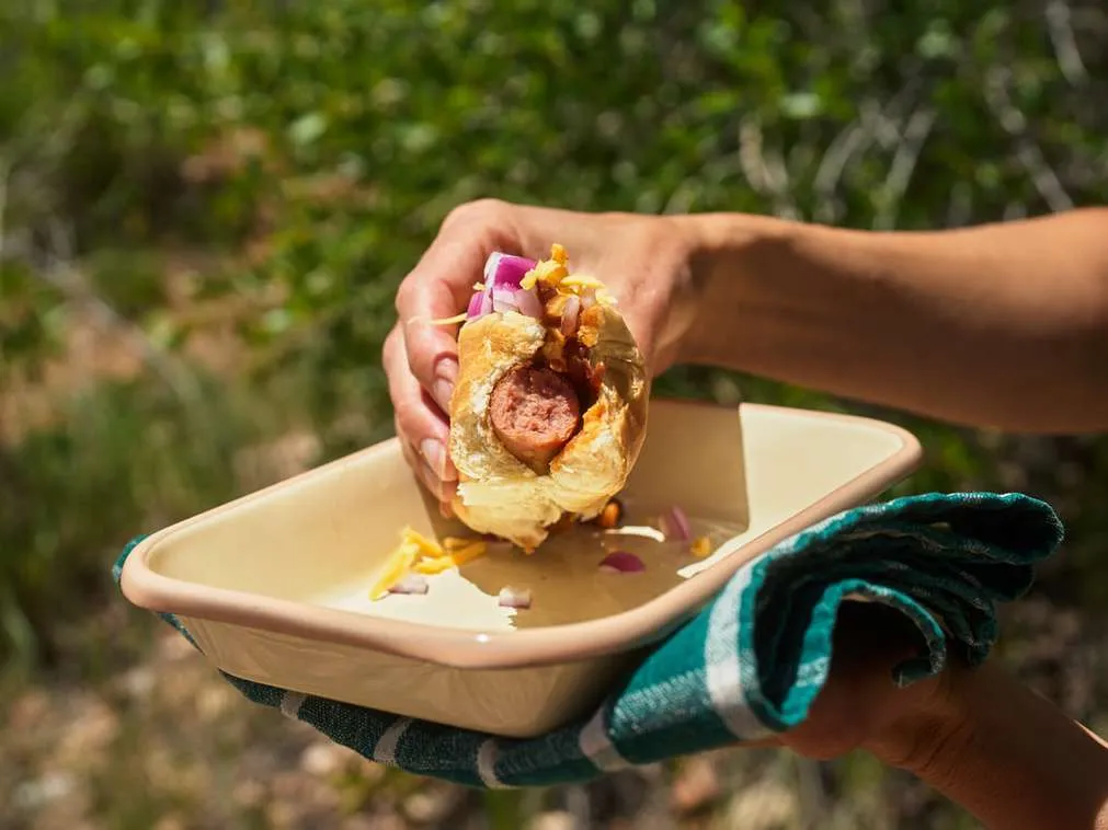 eating camping chili dogs with cheese and red onion for dinner